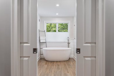 Inspiration for a large farmhouse master white tile and subway tile porcelain tile, brown floor, single-sink and shiplap wall bathroom remodel in Boston with shaker cabinets, white cabinets, a one-piece toilet, gray walls, an undermount sink, marble countertops, a hinged shower door and a freestanding vanity