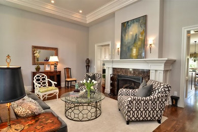 Mid-sized elegant enclosed medium tone wood floor living room photo in Orlando with gray walls, a standard fireplace, a plaster fireplace and no tv
