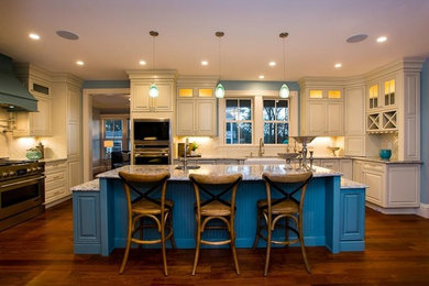 Inspiration for a large traditional u-shaped open plan kitchen in Boston with a farmhouse sink, raised-panel cabinets, white cabinets, white splashback, stainless steel appliances, medium hardwood floors, with island and brown floor.