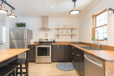 Inspiration for a mid-sized rustic l-shaped ceramic tile and beige floor kitchen remodel in Other with a double-bowl sink, flat-panel cabinets, dark wood cabinets, wood countertops, white backsplash, wood backsplash, stainless steel appliances and an island