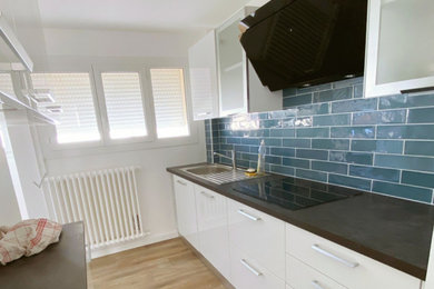 Modelo de cocina minimalista de tamaño medio sin isla con salpicadero azul, salpicadero de azulejos tipo metro y encimeras negras