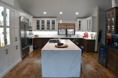 高級な広いモダンスタイルのおしゃれなキッチン (ダブルシンク、濃色木目調キャビネット、大理石カウンター、白いキッチンパネル、大理石のキッチンパネル、シルバーの調理設備、クッションフロア、茶色い床、白いキッチンカウンター、三角天井) の写真