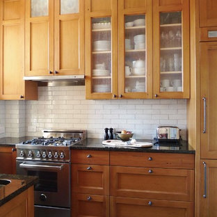 Bild på ett litet lantligt kök, med en nedsänkt diskho, skåp i shakerstil, skåp i mellenmörkt trä, granitbänkskiva, vitt stänkskydd, stänkskydd i keramik, rostfria vitvaror, skiffergolv och grått golv