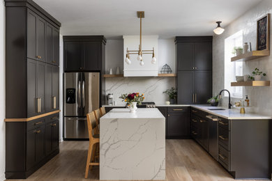 Large transitional u-shaped brown floor and medium tone wood floor eat-in kitchen photo in Detroit with an undermount sink, shaker cabinets, quartz countertops, white backsplash, stainless steel appliances, an island, white countertops and black cabinets