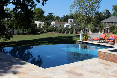 Photo of a mid-sized modern backyard rectangular infinity pool in DC Metro with a pool house and natural stone pavers.
