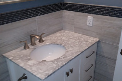Bathroom - transitional gray tile and porcelain tile porcelain tile, gray floor and single-sink bathroom idea in Miami with recessed-panel cabinets, white cabinets, blue walls, an undermount sink, marble countertops and gray countertops
