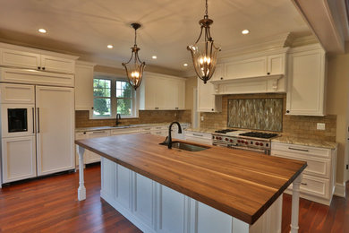 Inspiration for a large rustic l-shaped medium tone wood floor eat-in kitchen remodel in Philadelphia with an undermount sink, recessed-panel cabinets, white cabinets, wood countertops, beige backsplash, stone tile backsplash, stainless steel appliances and an island