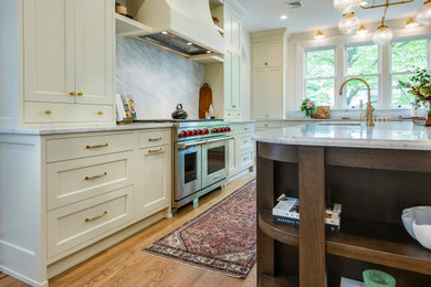 Design ideas for a large traditional l-shaped eat-in kitchen in Philadelphia with an undermount sink, flat-panel cabinets, white cabinets, marble benchtops, marble splashback, stainless steel appliances, light hardwood floors and with island.
