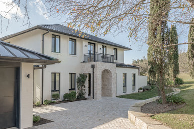 Photo of a large transitional two-storey brick beige house exterior in Wollongong with a gable roof, a metal roof and a black roof.