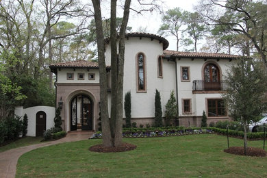 Example of a large tuscan white three-story stucco house exterior design in Houston with a tile roof