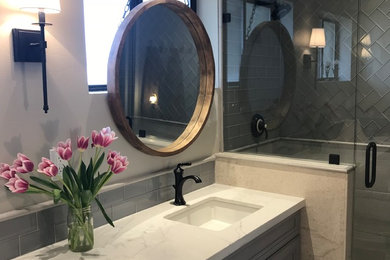 Example of a mid-sized country kids' blue tile and glass tile limestone floor and beige floor alcove shower design in Phoenix with flat-panel cabinets, blue cabinets, a two-piece toilet, gray walls, an undermount sink, quartz countertops, a hinged shower door and white countertops