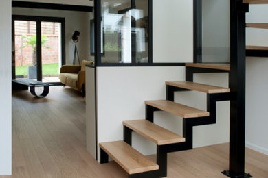 Cette photo montre un grand escalier tendance en U avec des marches en bois, des contremarches en métal, un garde-corps en métal et palier.