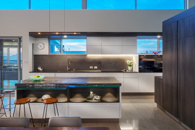 Inspiration for a large beach style galley open plan kitchen in Perth with an undermount sink, white cabinets, granite benchtops, brown splashback, black appliances, travertine floors, with island and beige floor.