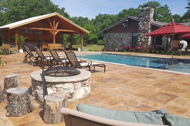Photo of a mid-sized tropical backyard rectangular natural pool in Dallas with natural stone pavers.