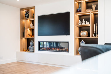 Inspiration for a large modern open concept living room in Sydney with white walls, laminate floors, a standard fireplace, a plaster fireplace surround, a built-in media wall and brown floor.