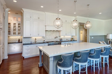 Inspiration for a large transitional single-wall dark wood floor open concept kitchen remodel in Phoenix with a farmhouse sink, recessed-panel cabinets, white cabinets, white backsplash, subway tile backsplash, stainless steel appliances and an island