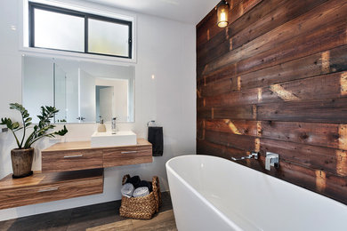 Design ideas for a contemporary master bathroom in Newcastle - Maitland with flat-panel cabinets, medium wood cabinets, a freestanding tub, white walls, a vessel sink and brown floor.