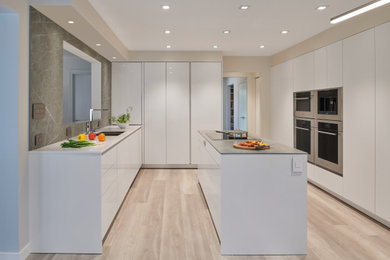 Mid-sized trendy u-shaped vinyl floor and gray floor eat-in kitchen photo in DC Metro with an undermount sink, flat-panel cabinets, white cabinets, quartzite countertops, gray backsplash, quartz backsplash, stainless steel appliances, an island and gray countertops