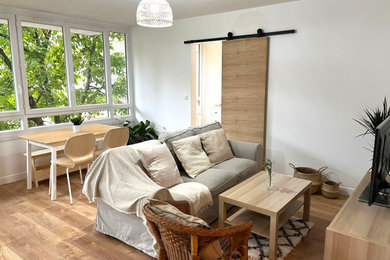 Modelo de sala de estar abierta minimalista grande sin chimenea con paredes blancas, suelo de madera clara, televisor independiente y suelo beige