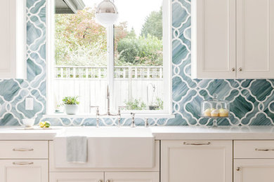 Inspiration for a mid-sized transitional u-shaped light wood floor kitchen remodel in Portland with a farmhouse sink, recessed-panel cabinets, white cabinets, quartz countertops, green backsplash, mosaic tile backsplash and paneled appliances