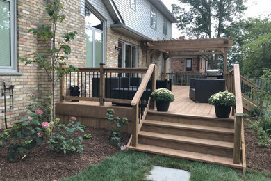 Mid-sized trendy wood railing back porch photo in Toronto with a pergola