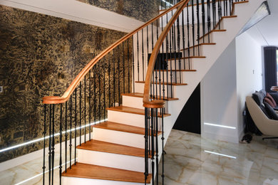 This is an example of a medium sized traditional wood curved metal railing staircase in Buckinghamshire with wood risers.