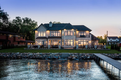 Inspiration for a huge timeless two-story stone house exterior remodel in Other with a hip roof, a shingle roof and a black roof