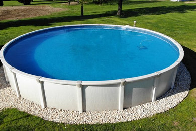 Modelo de piscina elevada de tamaño medio redondeada en patio trasero con gravilla