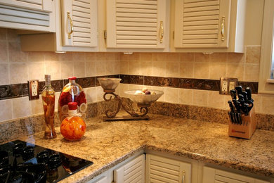 Mid-sized elegant l-shaped kitchen photo in Chicago with a double-bowl sink, white cabinets, granite countertops, beige backsplash, ceramic backsplash, black appliances, an island and louvered cabinets
