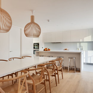 Photo of a large modern kitchen/dining room in London with white walls, light hardwood flooring and no fireplace.
