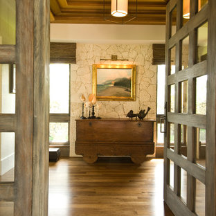 This is an example of a tropical foyer in Hawaii with dark hardwood floors and a glass front door.