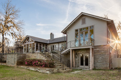 Example of a large farmhouse beige split-level stone exterior home design in New Orleans with a shingle roof
