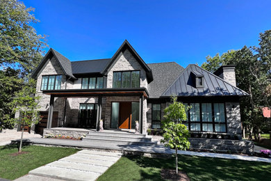 Design ideas for an expansive transitional two-storey grey house exterior in Toronto with stone veneer, a gable roof, a mixed roof and a grey roof.