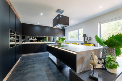 Design ideas for a medium sized contemporary l-shaped kitchen/diner in Edinburgh with a built-in sink, flat-panel cabinets, black cabinets, composite countertops, grey splashback, mirror splashback, black appliances, dark hardwood flooring, an island, black floors and multicoloured worktops.