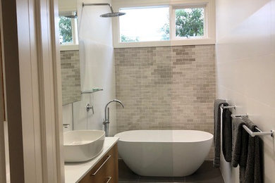 This is an example of a mid-sized contemporary bathroom in Melbourne with medium wood cabinets, a freestanding tub, a vessel sink, quartzite benchtops, an open shower and white benchtops.