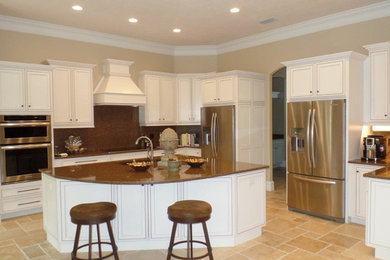 Example of a trendy travertine floor kitchen design in Tampa with an undermount sink, flat-panel cabinets, white cabinets, quartzite countertops, metallic backsplash and stainless steel appliances