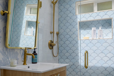 Example of a small beach style blue tile and porcelain tile porcelain tile, beige floor, single-sink and wallpaper bathroom design in Other with louvered cabinets, light wood cabinets, blue walls, an integrated sink, white countertops, a niche and a freestanding vanity