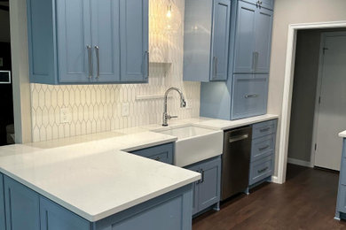 Inspiration for a mid-sized timeless dark wood floor kitchen remodel in Oklahoma City with a farmhouse sink, beaded inset cabinets, blue cabinets, quartz countertops, white backsplash, stainless steel appliances, a peninsula and white countertops