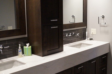 Photo of a large modern master bathroom in Minneapolis with shaker cabinets, dark wood cabinets, a two-piece toilet, gray tile, glass tile, grey walls, porcelain floors, an undermount sink and quartzite benchtops.