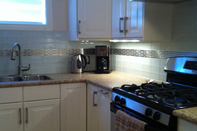 Example of a classic l-shaped kitchen design in Toronto with a drop-in sink, raised-panel cabinets, white cabinets, laminate countertops, stainless steel appliances and a peninsula