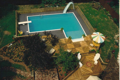 This is an example of a large modern back l-shaped above ground swimming pool in Detroit with decking and a water slide.