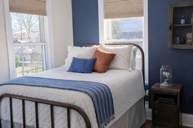 Example of a mid-sized urban guest medium tone wood floor and brown floor bedroom design in New York with blue walls