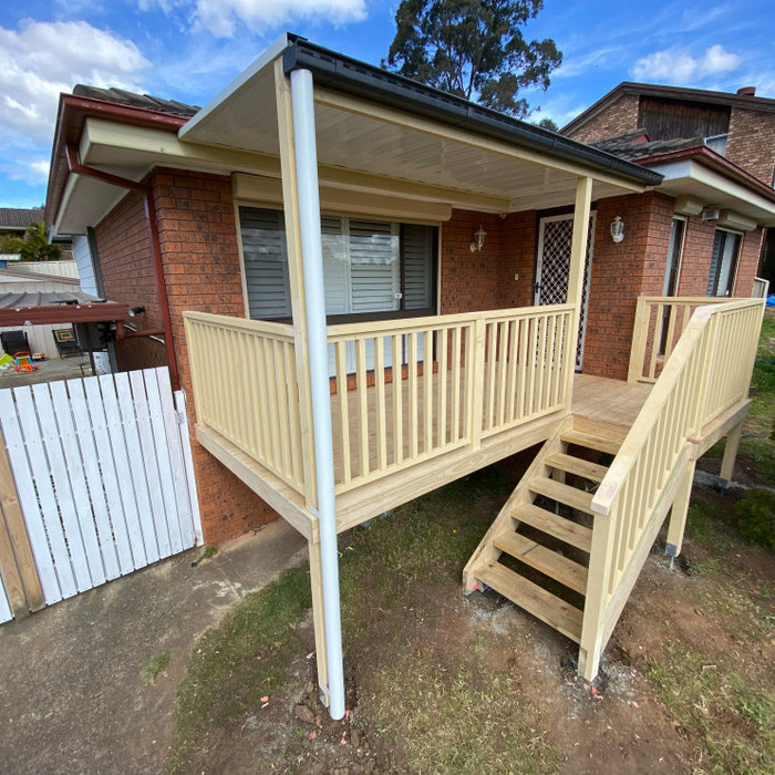 This is an example of a mid-sized modern ground level deck in Sydney with a pergola and wood railing.