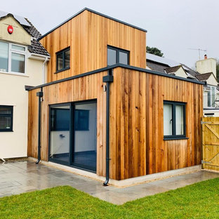 Inredning av ett modernt mellanstort svart hus, med två våningar, platt tak och levande tak