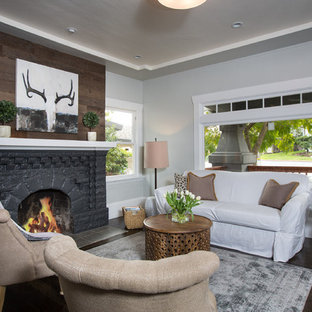Idee per un piccolo soggiorno american style aperto con pareti grigie, parquet scuro, camino classico, cornice del camino in pietra e nessuna TV