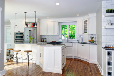 Inspiration for a timeless dark wood floor eat-in kitchen remodel in Columbus with a farmhouse sink, white cabinets, quartz countertops, white backsplash, subway tile backsplash, stainless steel appliances, an island and shaker cabinets