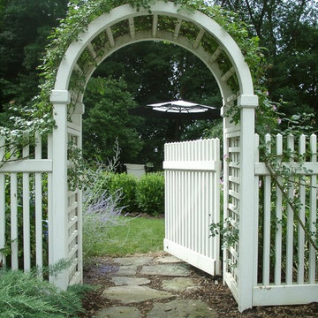 An arbor with climbing vines and a natural stone path welcomes you to the backya