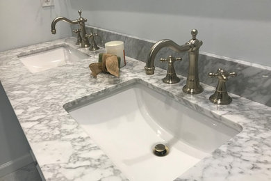 Small trendy master white tile and marble tile marble floor and white floor corner shower photo in Charleston with furniture-like cabinets, white cabinets, a two-piece toilet, an undermount sink, marble countertops, a hinged shower door and white countertops