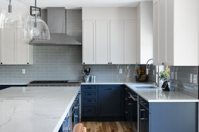 デンバーにある高級な広いトランジショナルスタイルのおしゃれなキッチン (アンダーカウンターシンク、シェーカースタイル扉のキャビネット、青いキャビネット、珪岩カウンター、グレーのキッチンパネル、ガラスタイルのキッチンパネル、シルバーの調理設備、淡色無垢フローリング、茶色い床、白いキッチンカウンター) の写真