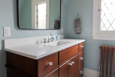 Mid-sized arts and crafts white tile and subway tile mosaic tile floor, multicolored floor and single-sink bathroom photo in Other with recessed-panel cabinets, medium tone wood cabinets, a two-piece toilet, blue walls, an undermount sink, quartz countertops, white countertops and a built-in vanity